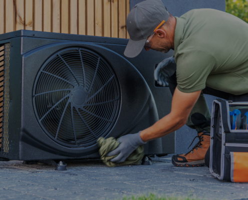 HVAC technician in British Columbia cleans an outdoor air conditioning unit, with a toolbox nearby for professional AC service.