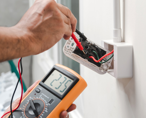 An HVAC technician in BC checks outlet voltage with a digital multimeter, showing 235 volts for safe electrical service.