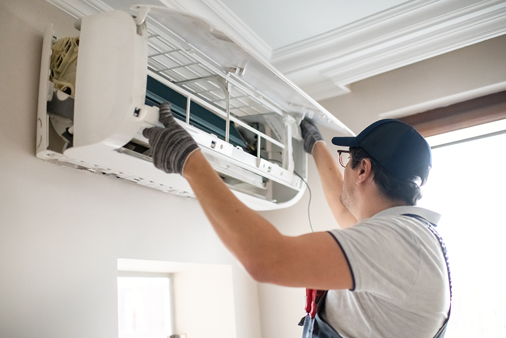 HVAC technician in gloves services a wall-mounted AC unit in a bright BC home, highlighting expert cooling system solutions. HVAC technician in gloves services a wall-mounted AC unit in a bright BC home, highlighting expert cooling system solutions.