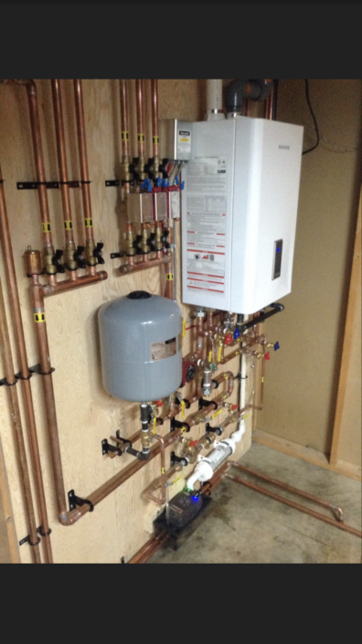 A neatly installed tankless water heater with copper pipes, valves, and an expansion tank in a BC utility room for HVAC services.