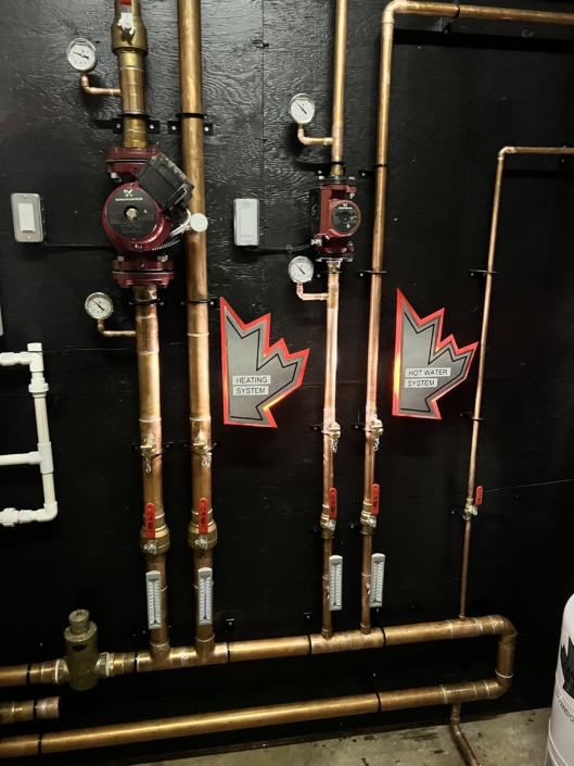 Neatly installed copper pipe systems for heating and hot water, with gauges and valves, shown in a British Columbia HVAC setup.